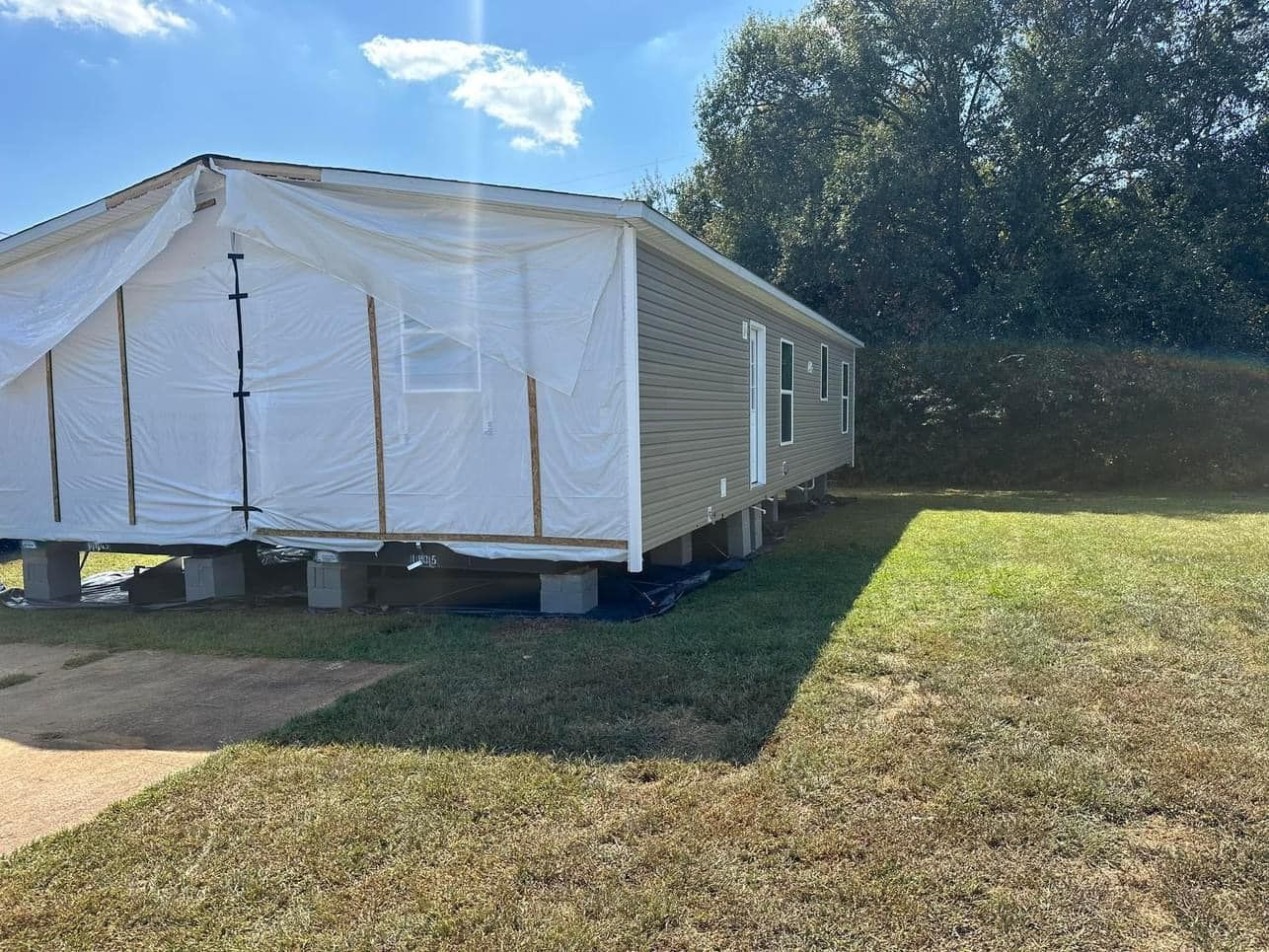 A mobile home is sitting in the middle of a grassy field.