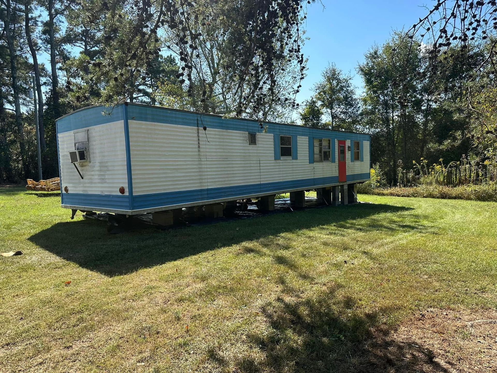 A blue and white mobile home is parked in a grassy field.