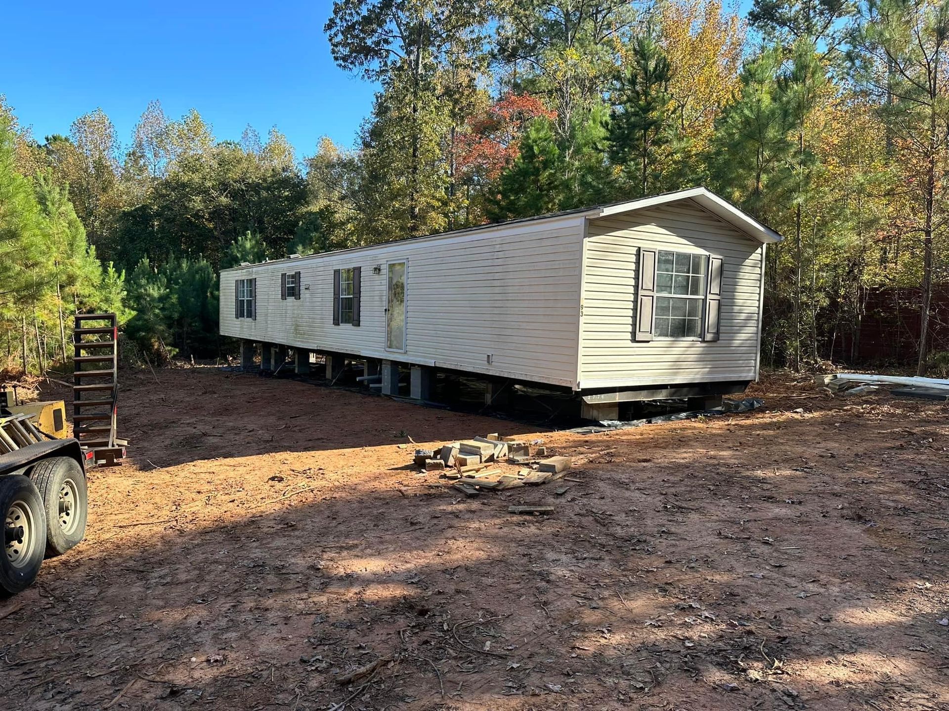 A mobile home is sitting in the middle of a dirt field.