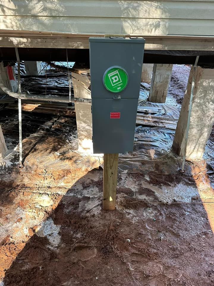 A black box is sitting on top of a wooden post in the dirt.