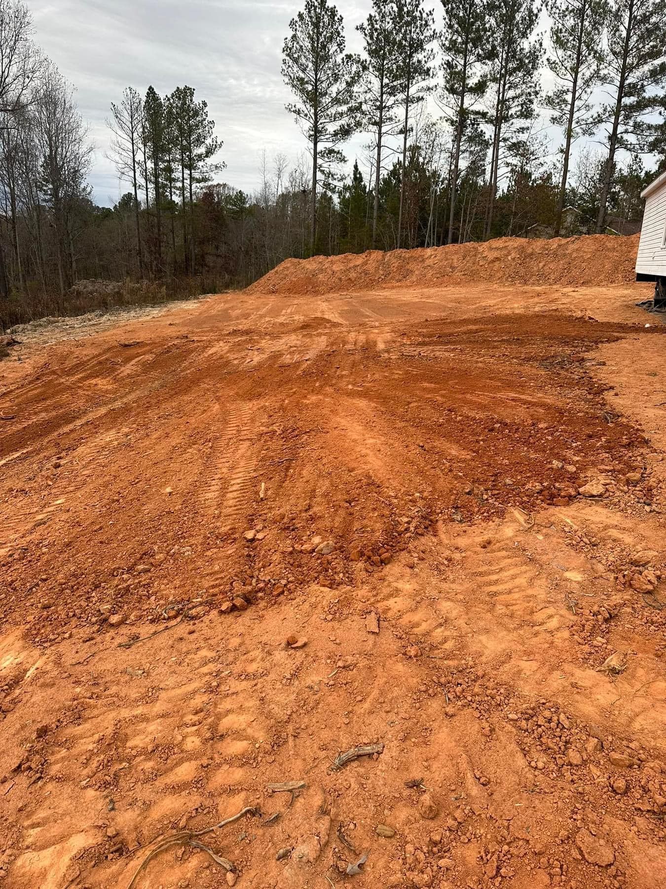 A large pile of dirt is sitting in the middle of a dirt road.