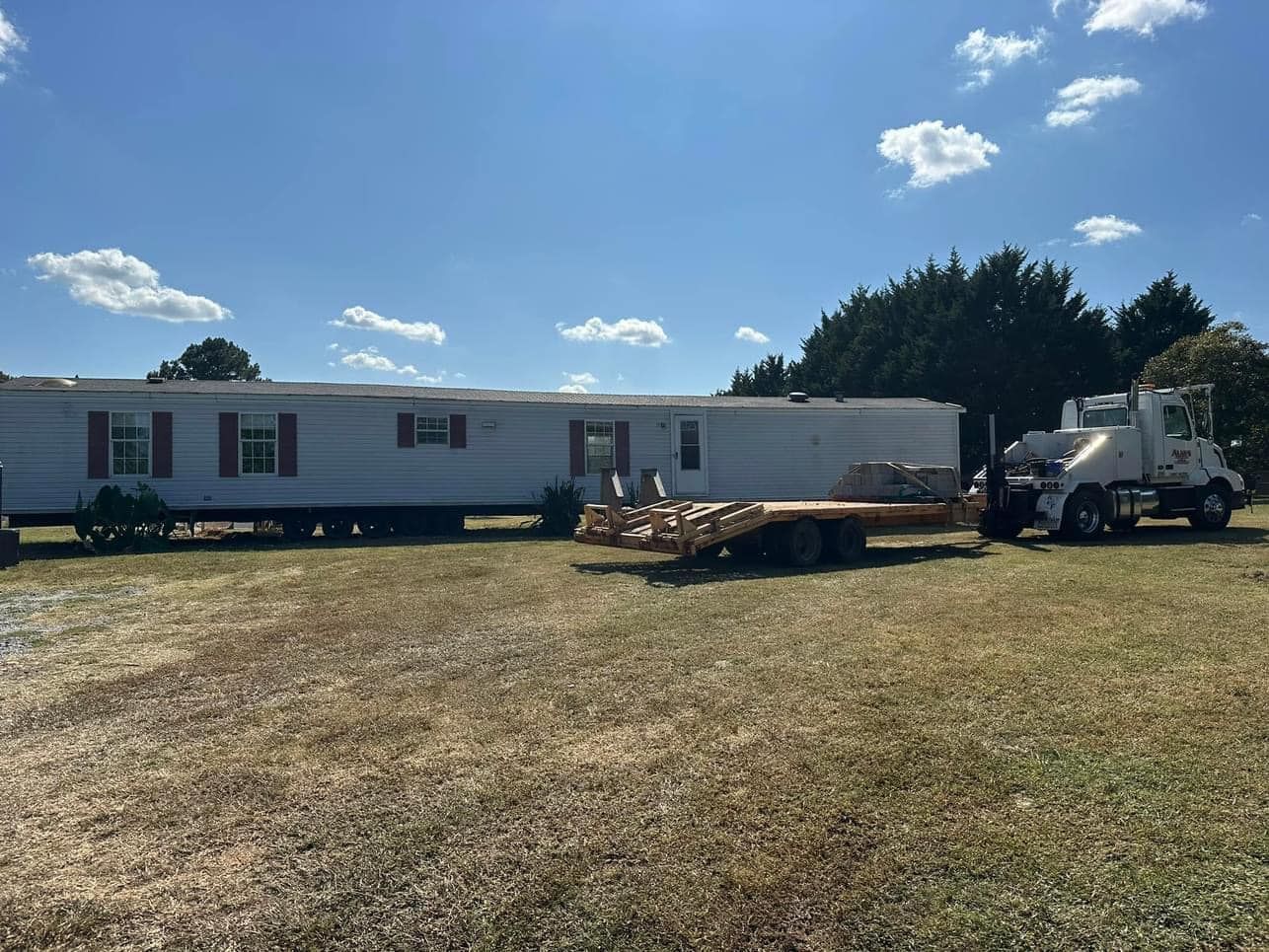 A trailer is being towed by a truck in a field.