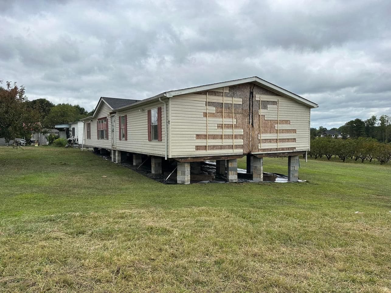 A mobile home is sitting on stilts in the middle of a grassy field.