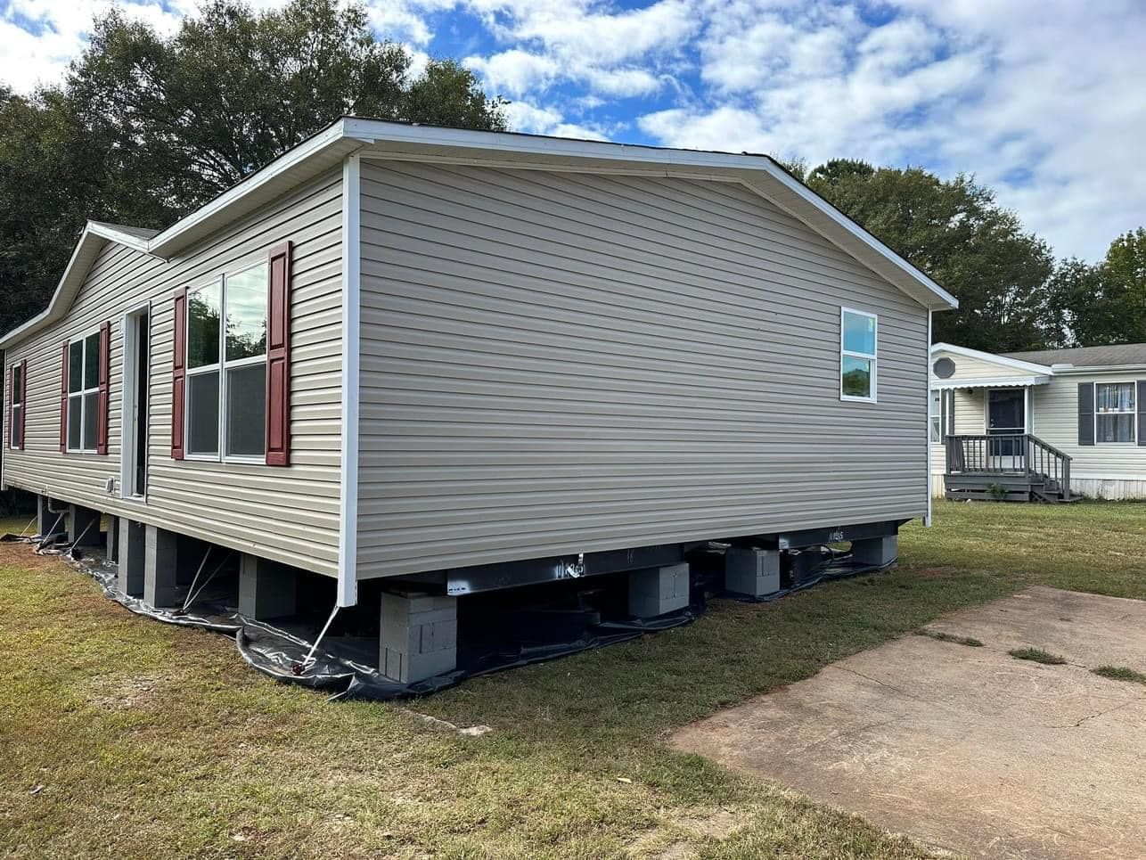 A mobile home is sitting on stilts in a grassy field.