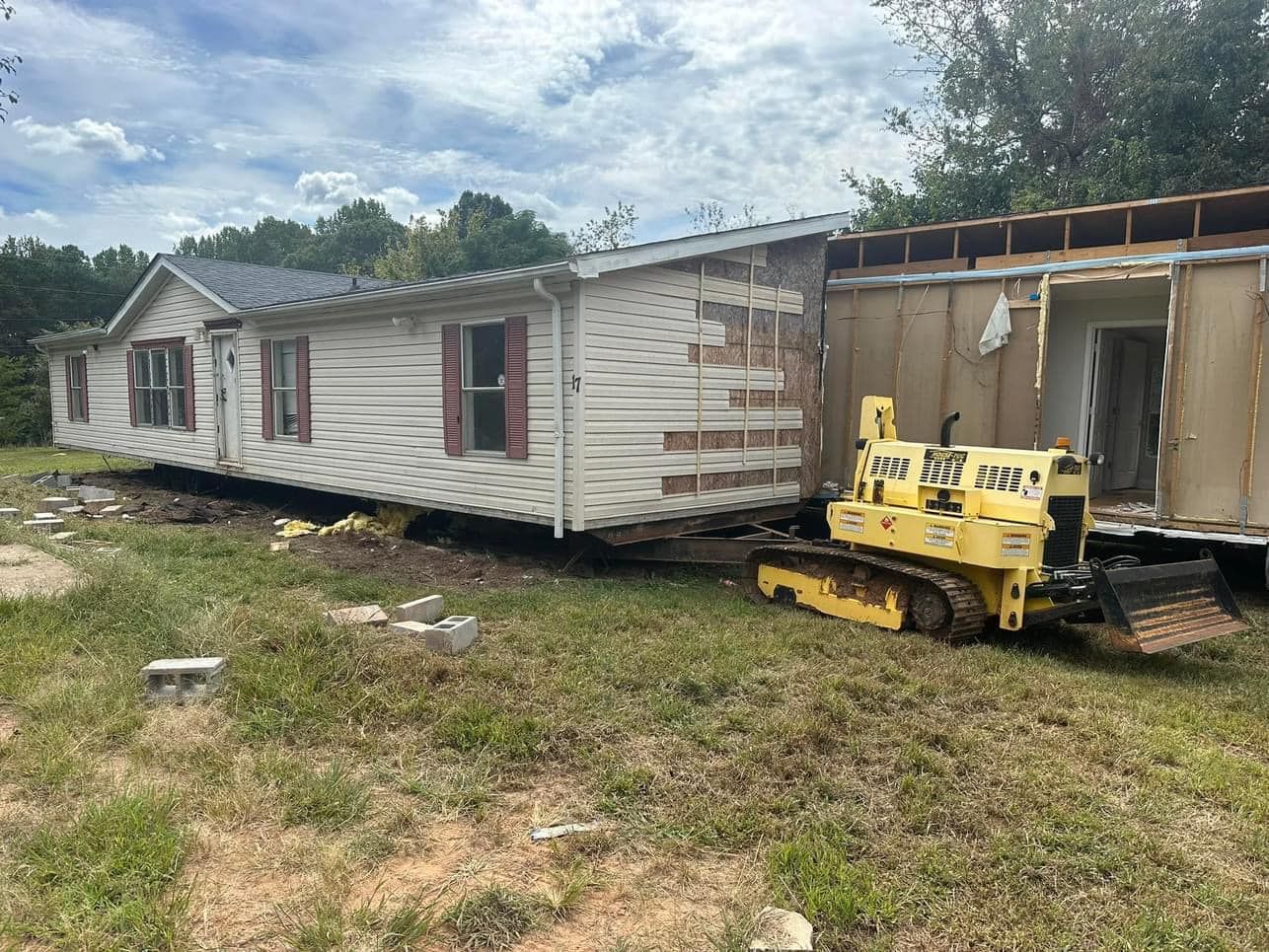 A mobile home is being moved by a bulldozer.