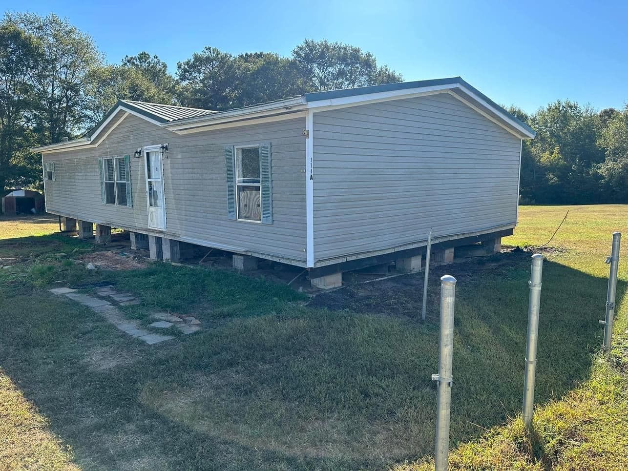 A mobile home is sitting in the middle of a grassy field.