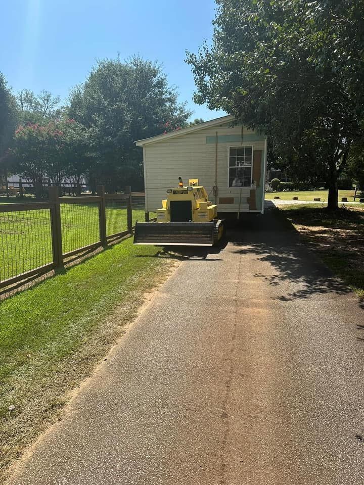 A yellow bulldozer is parked in front of a mobile home.