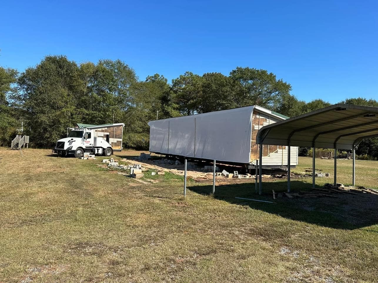 A truck is parked in a field next to a trailer.