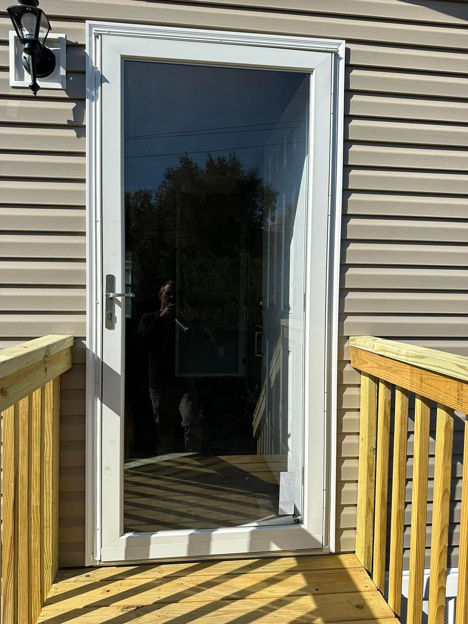 A white door with a glass door is sitting on a wooden deck.