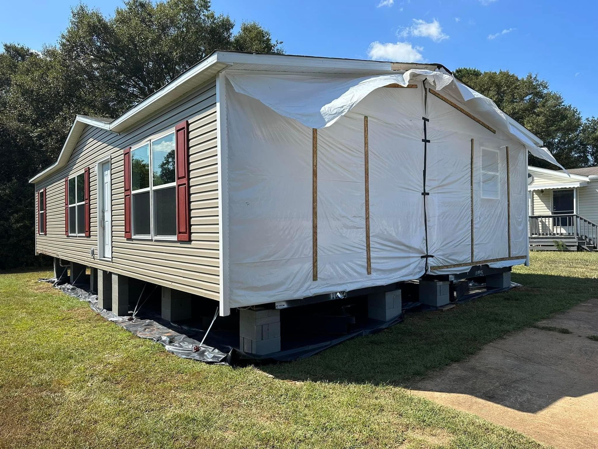 A mobile home with a white tarp on the side of it.
