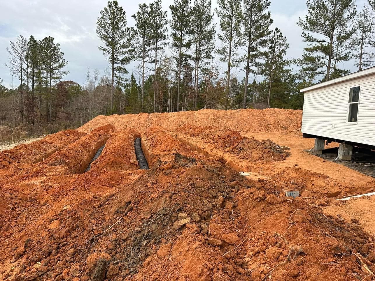 A mobile home is sitting in the dirt next to a pile of dirt.