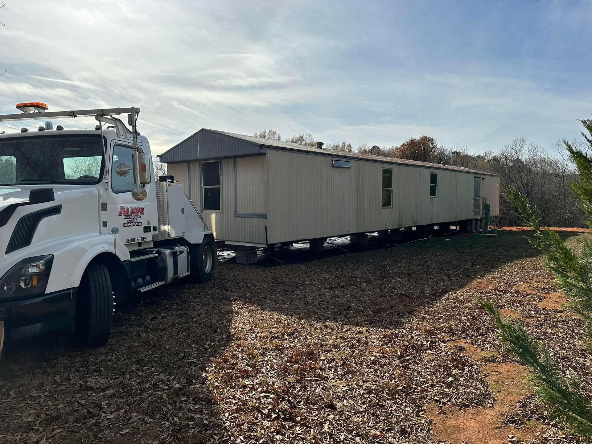 A white truck is towing a mobile home on a gravel road.