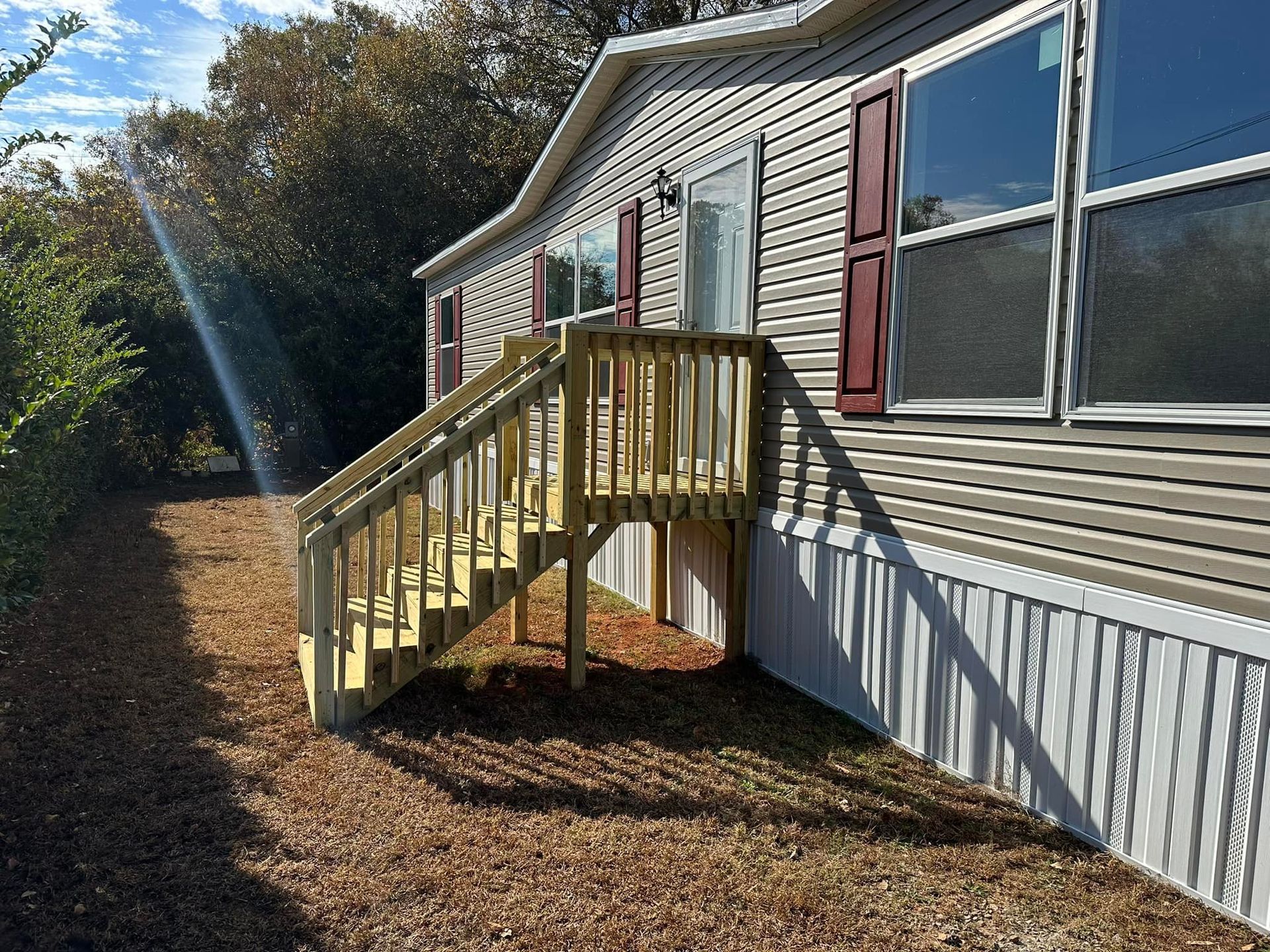 A mobile home with a wooden deck and stairs