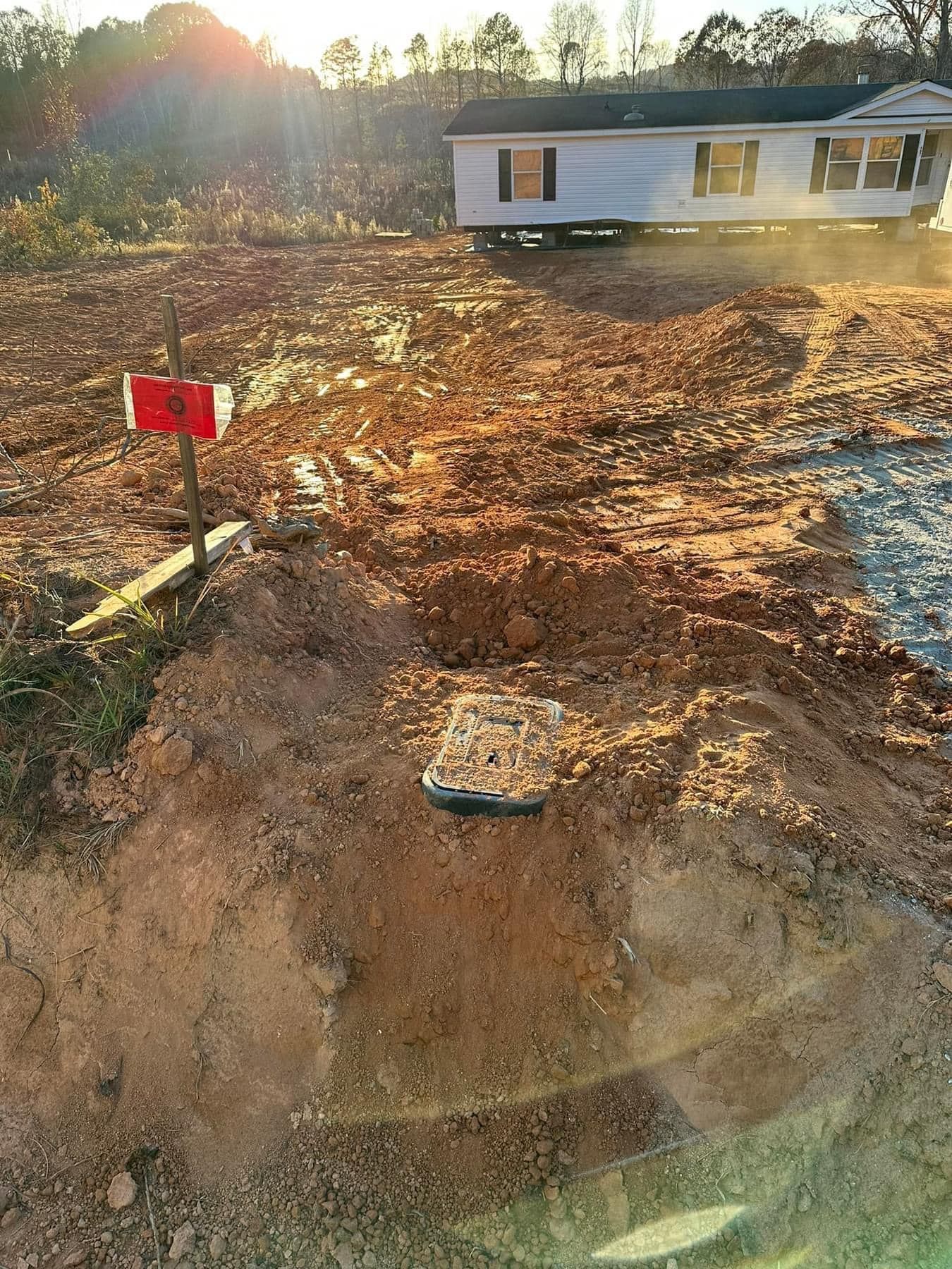 A mobile home is sitting in the middle of a dirt field.