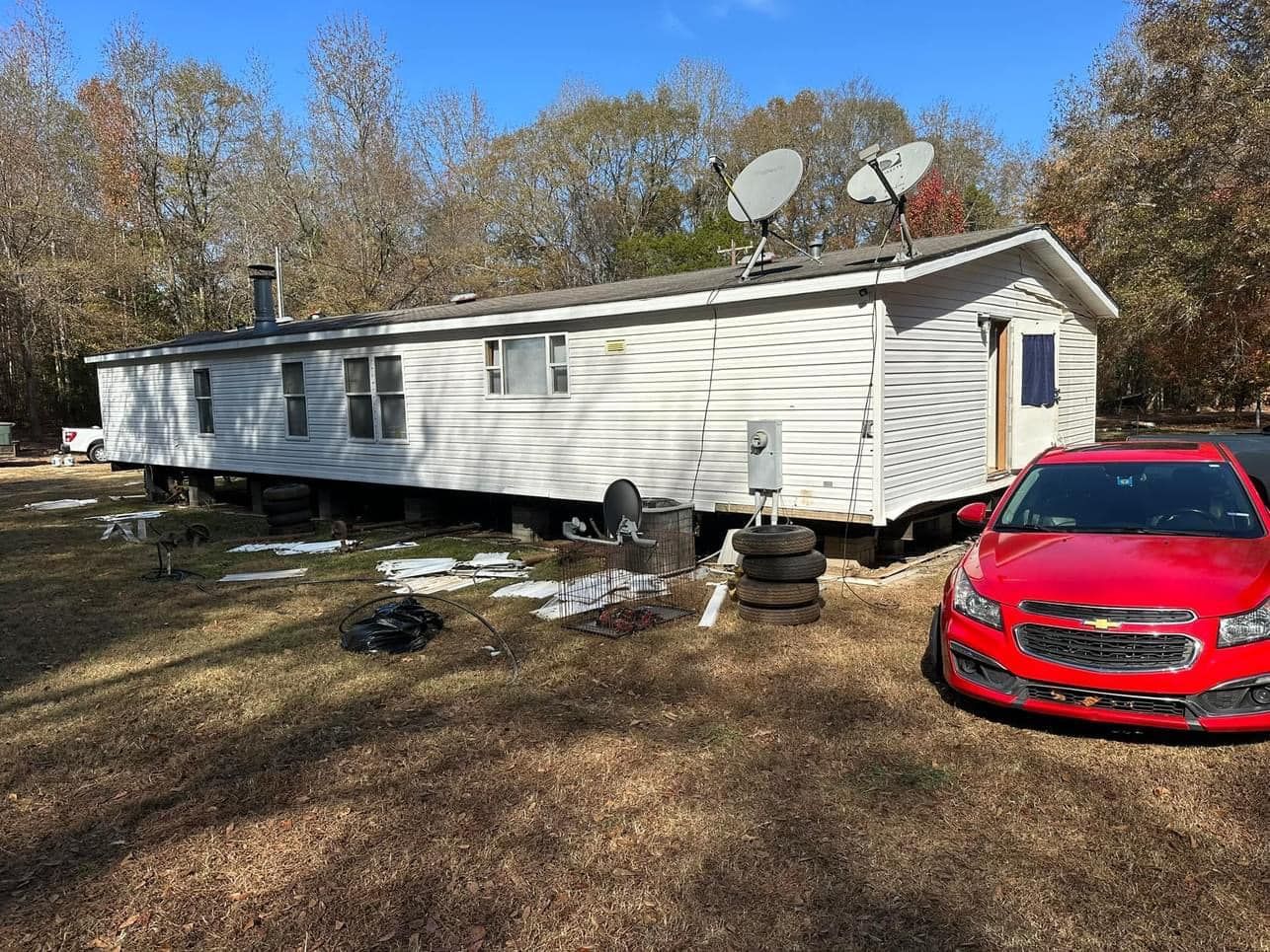 A red car is parked in front of a mobile home.