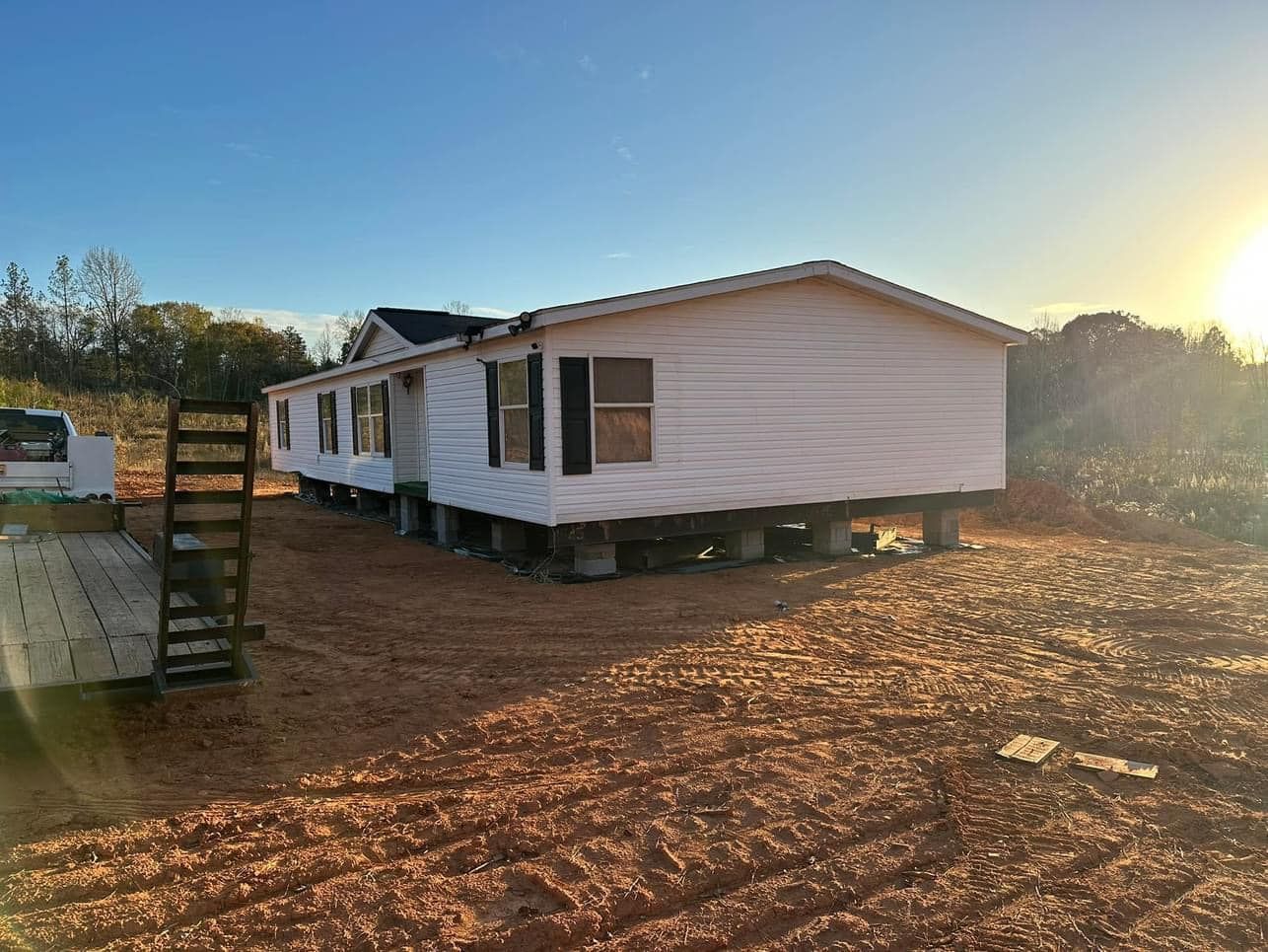 A mobile home is sitting on top of a dirt field.