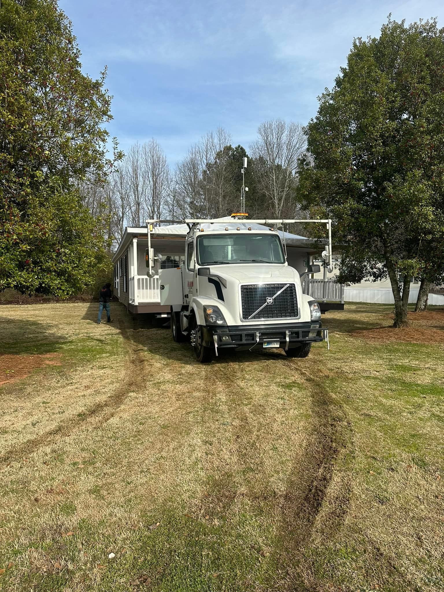 A white truck is parked in a grassy field next to a trailer.