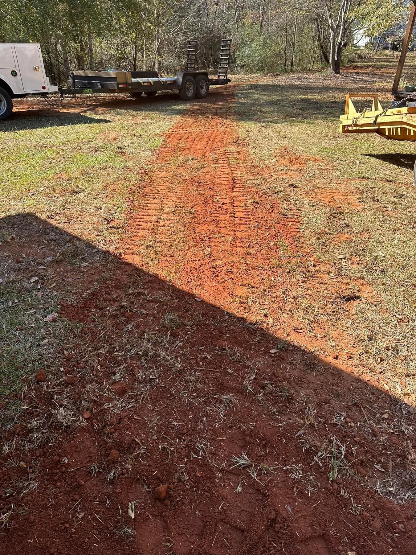 A white truck is parked in a grassy field next to a trailer.