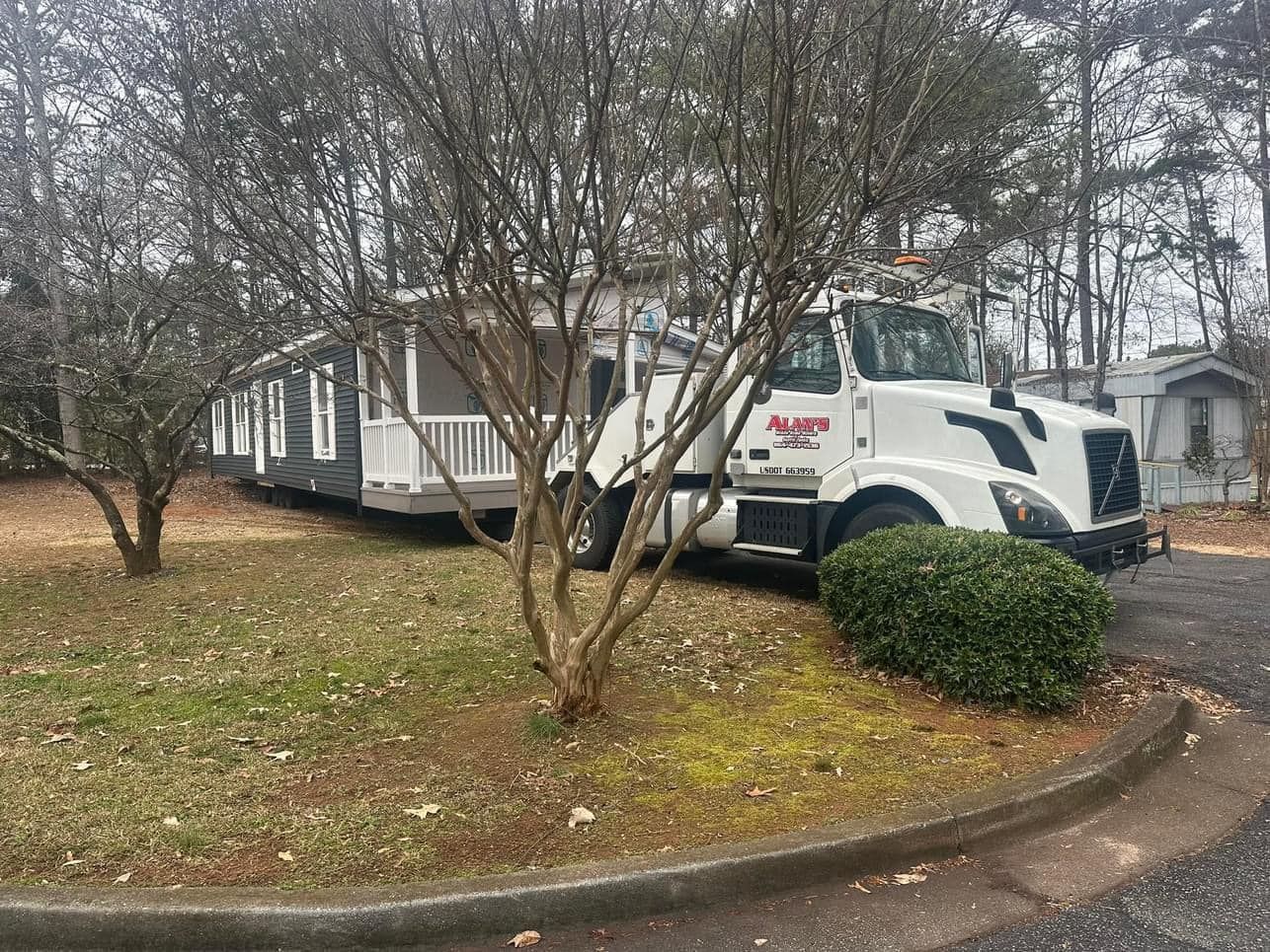 A white tow truck is parked in front of a mobile home.
