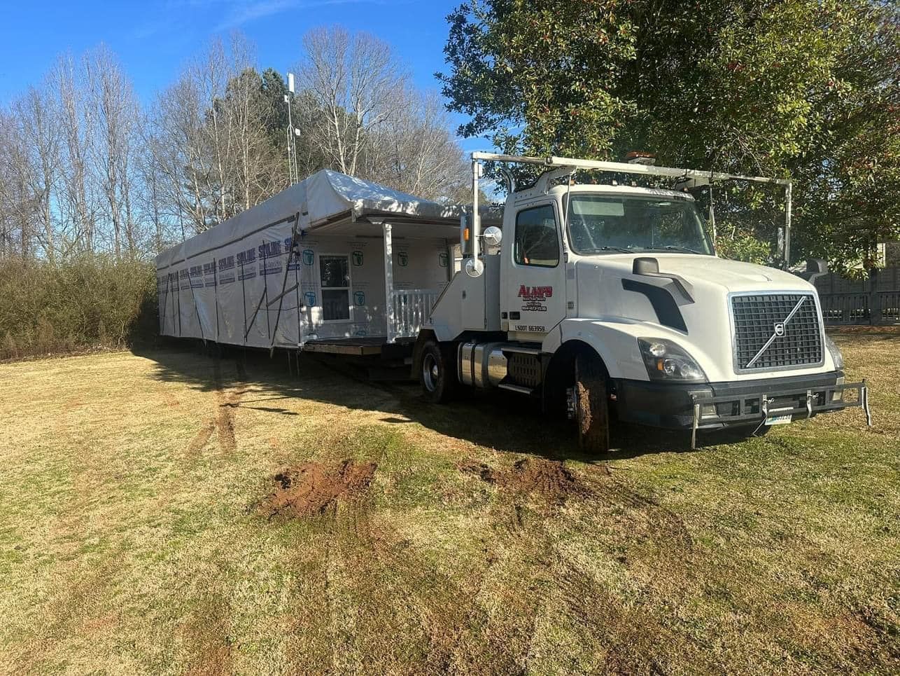 A white truck with a trailer attached to it is parked in a grassy field.