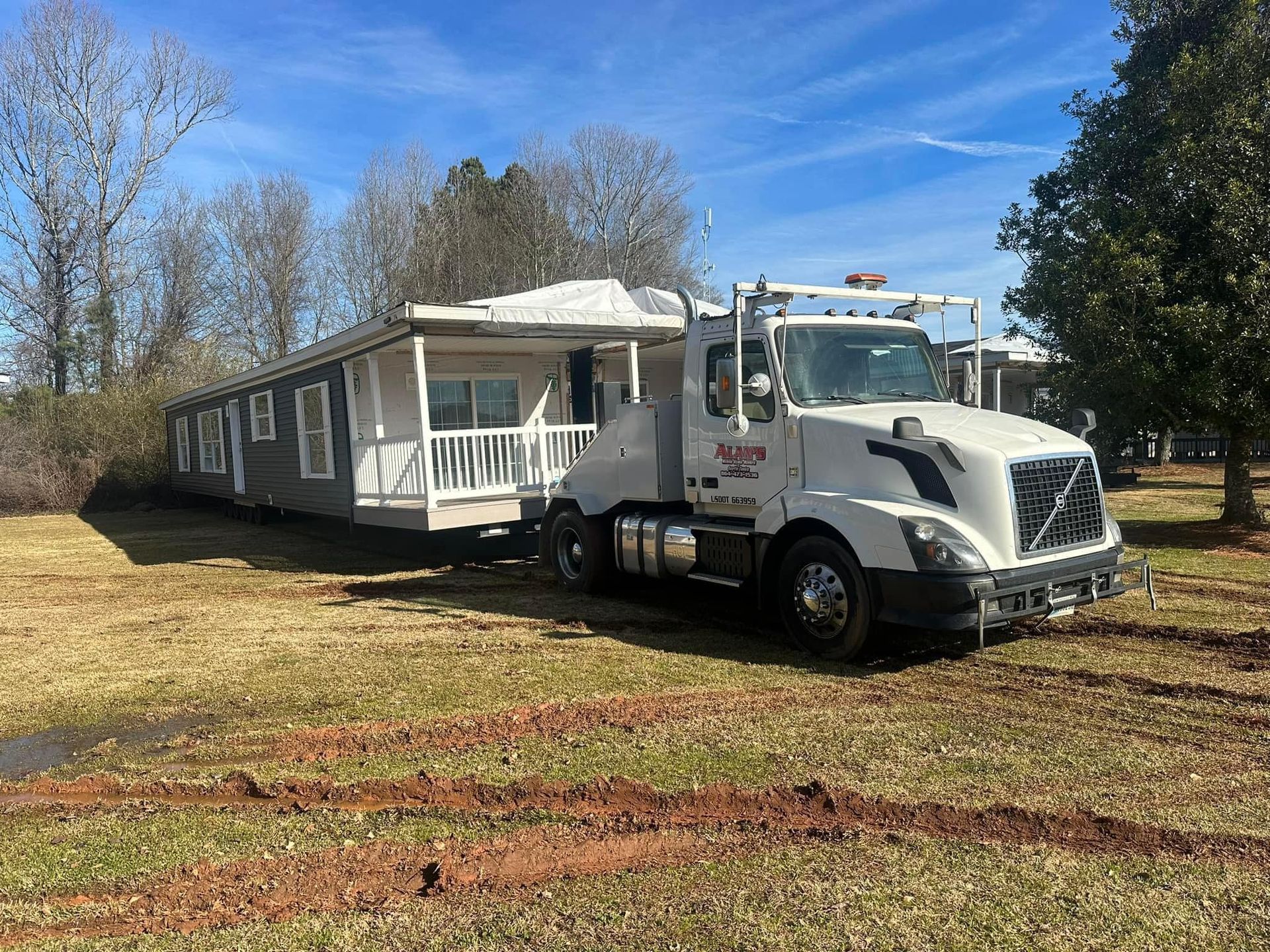 A white truck is towing a mobile home in a field.