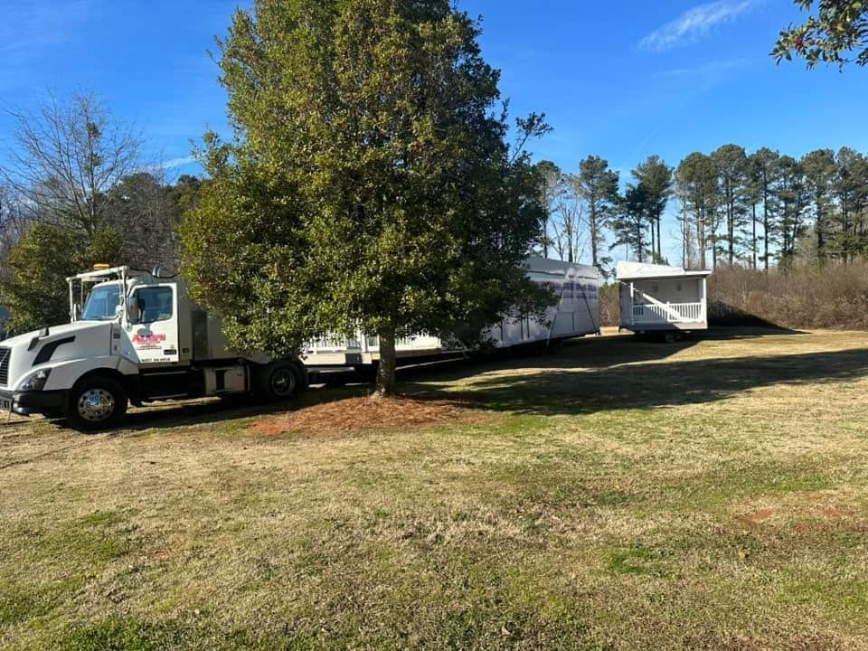 A white truck is towing a trailer in a grassy field.