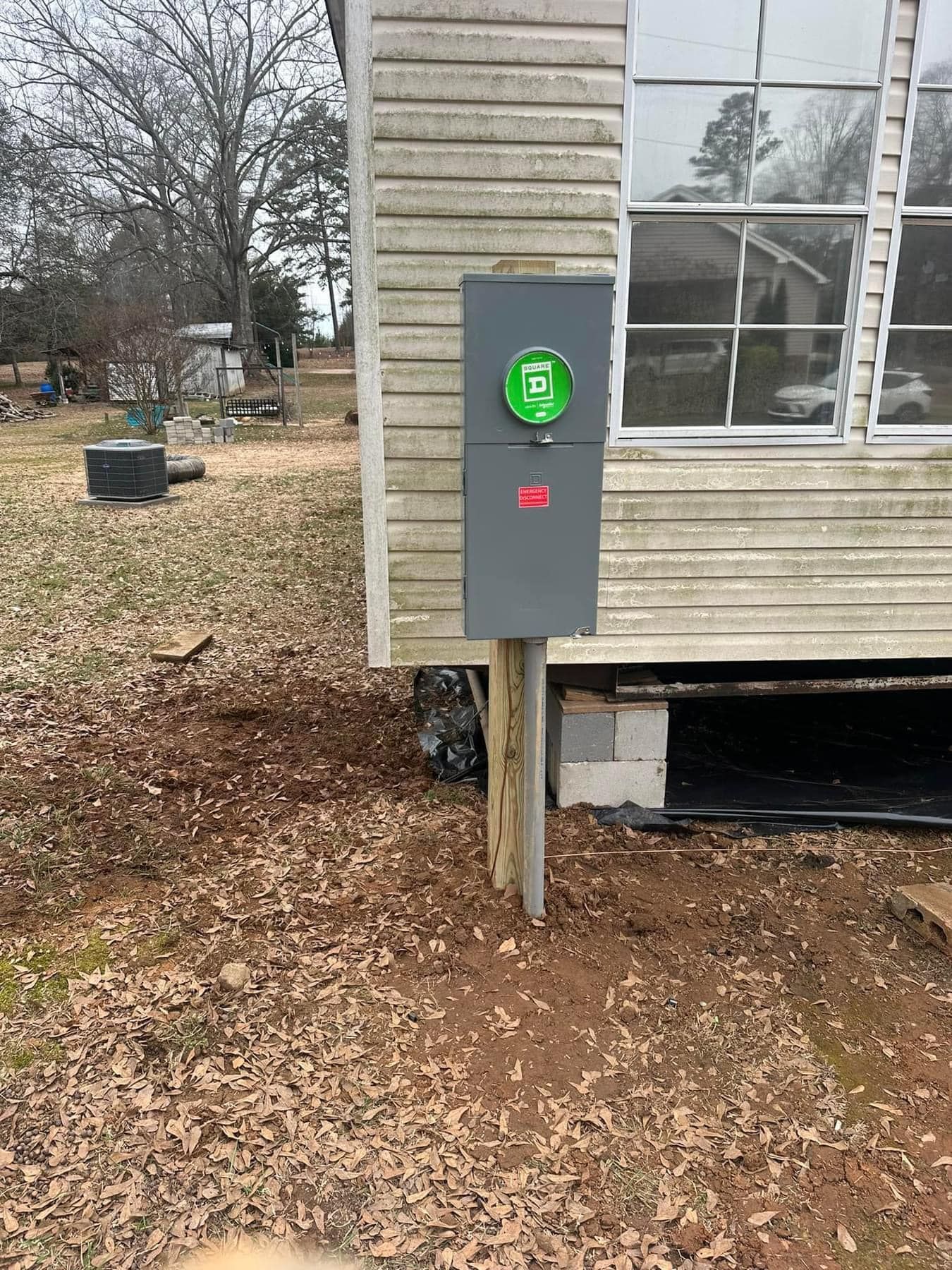 A gray box is sitting on a wooden post in front of a house.