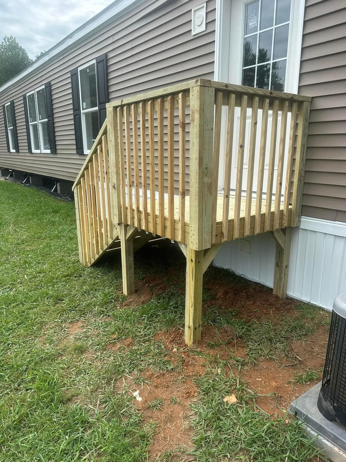 A wooden deck is sitting in front of a mobile home.