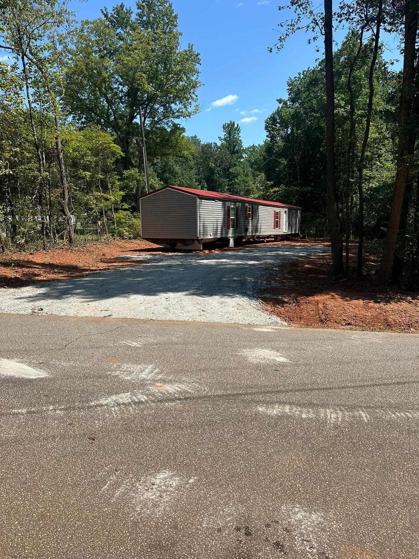 A mobile home is parked on the side of a road in the woods.