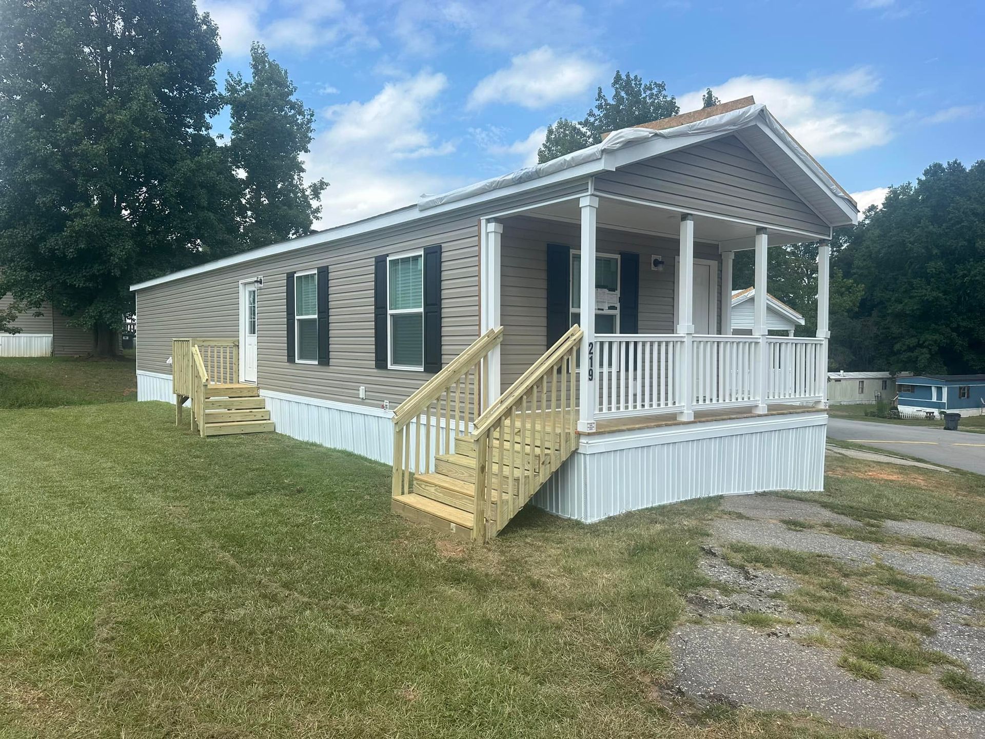 A mobile home with a large porch and stairs.