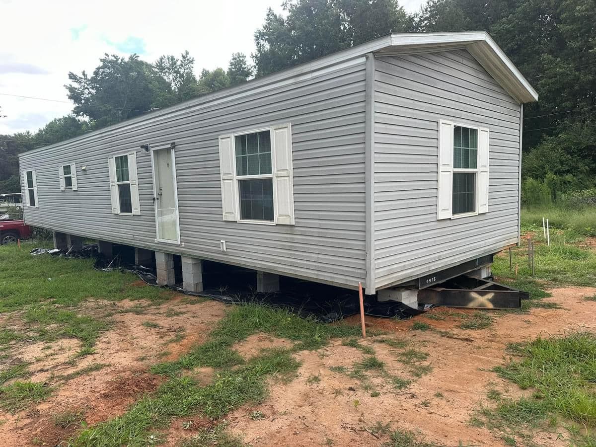 A mobile home is sitting on top of a dirt field.