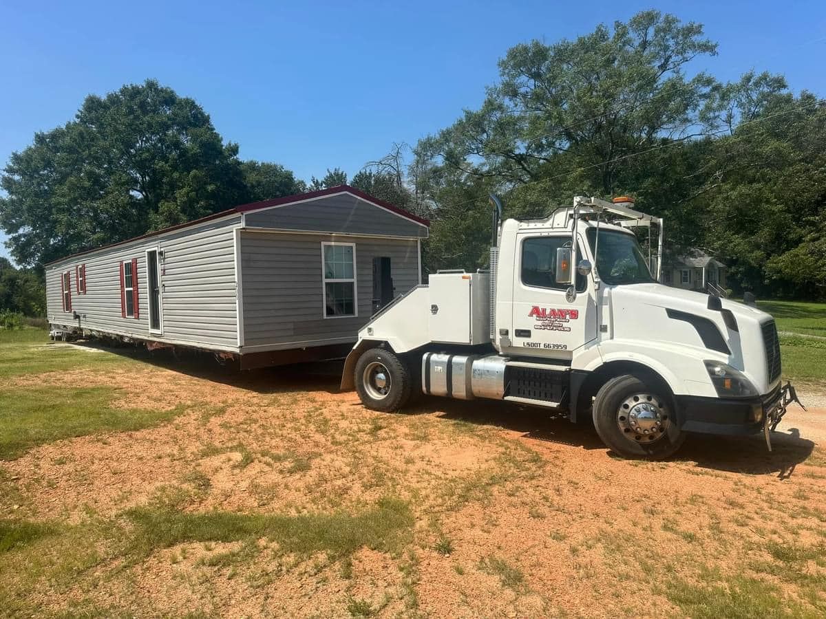 A mobile home is being towed by a tow truck.