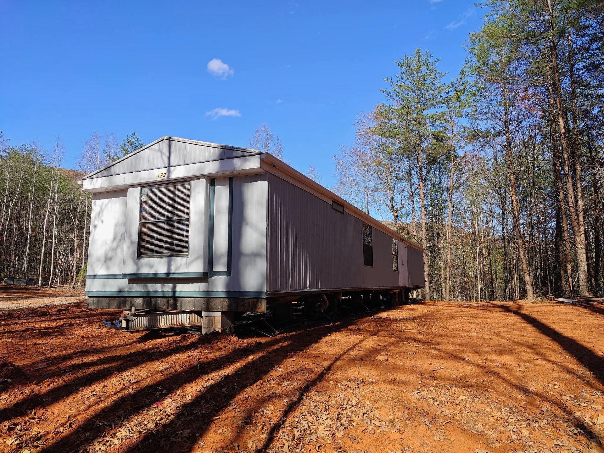 A mobile home is parked in the middle of a dirt road.