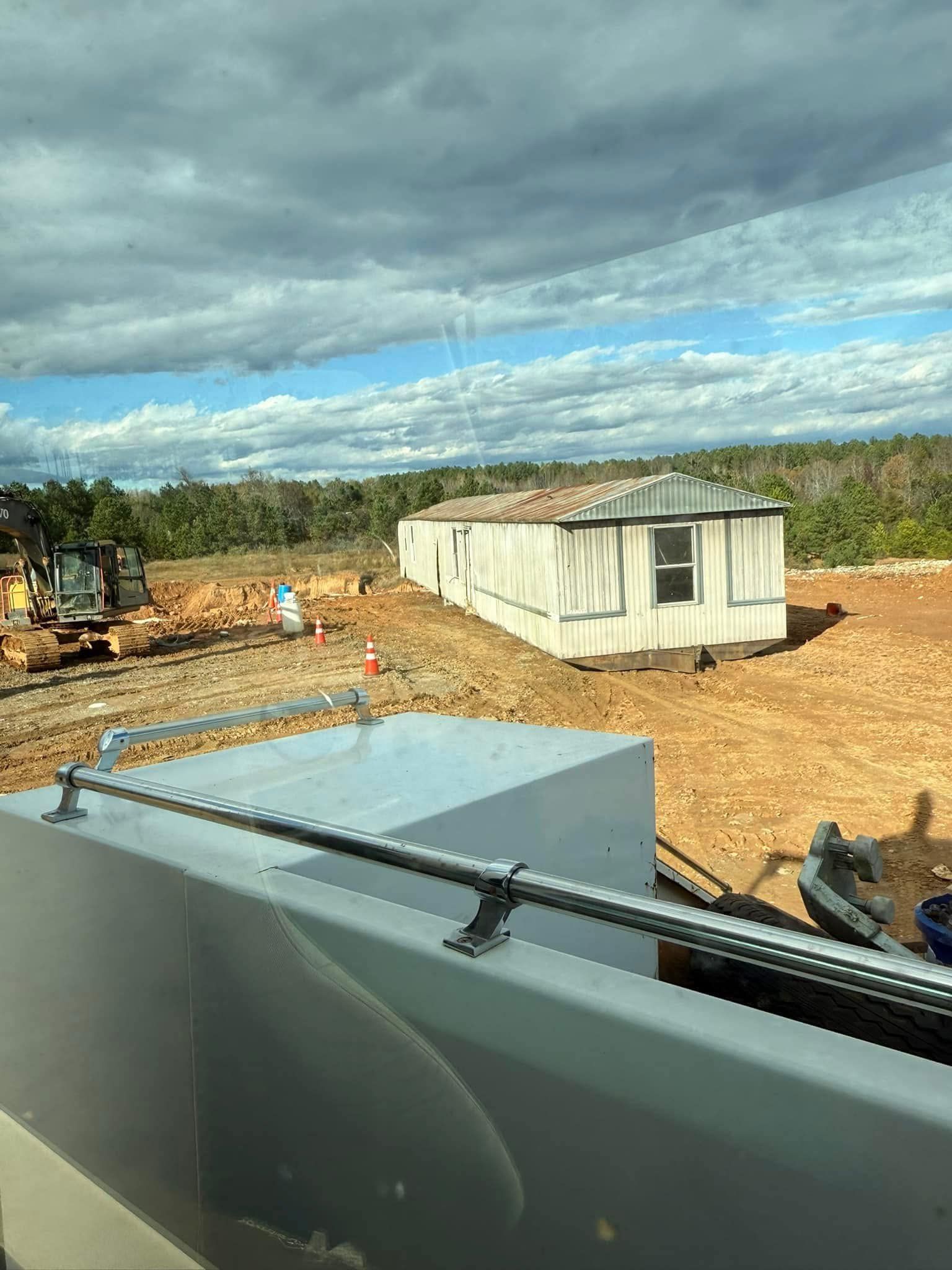 A mobile home is sitting in the middle of a dirt field.