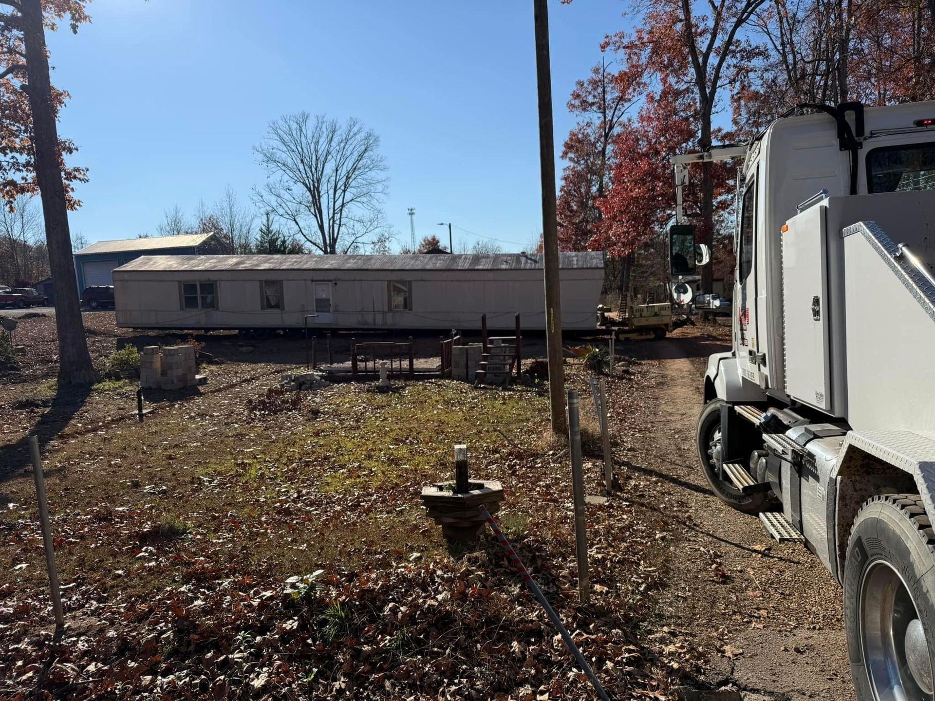 A white truck is parked in a field next to a mobile home.