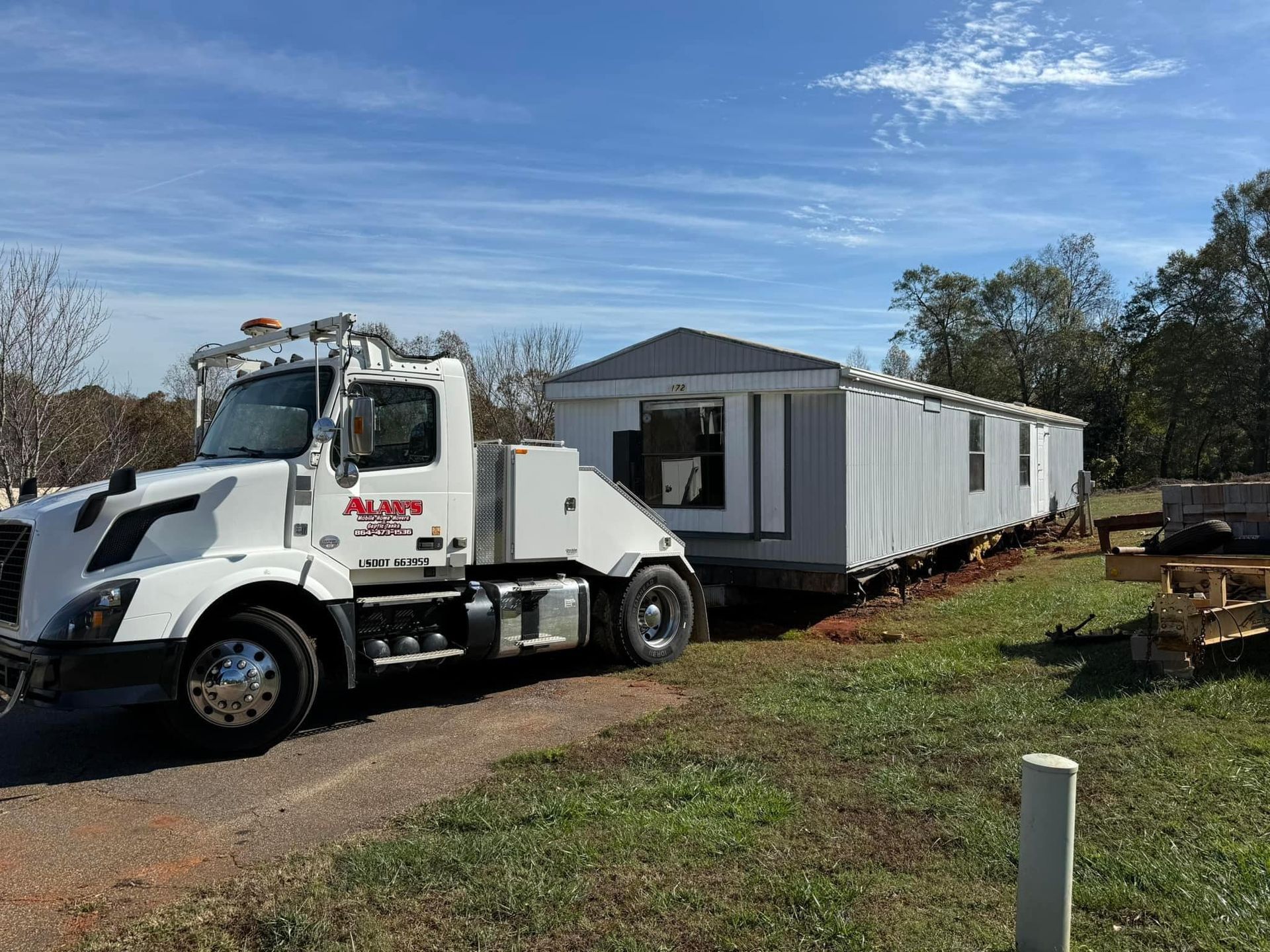 A tow truck is carrying a mobile home down a dirt road.