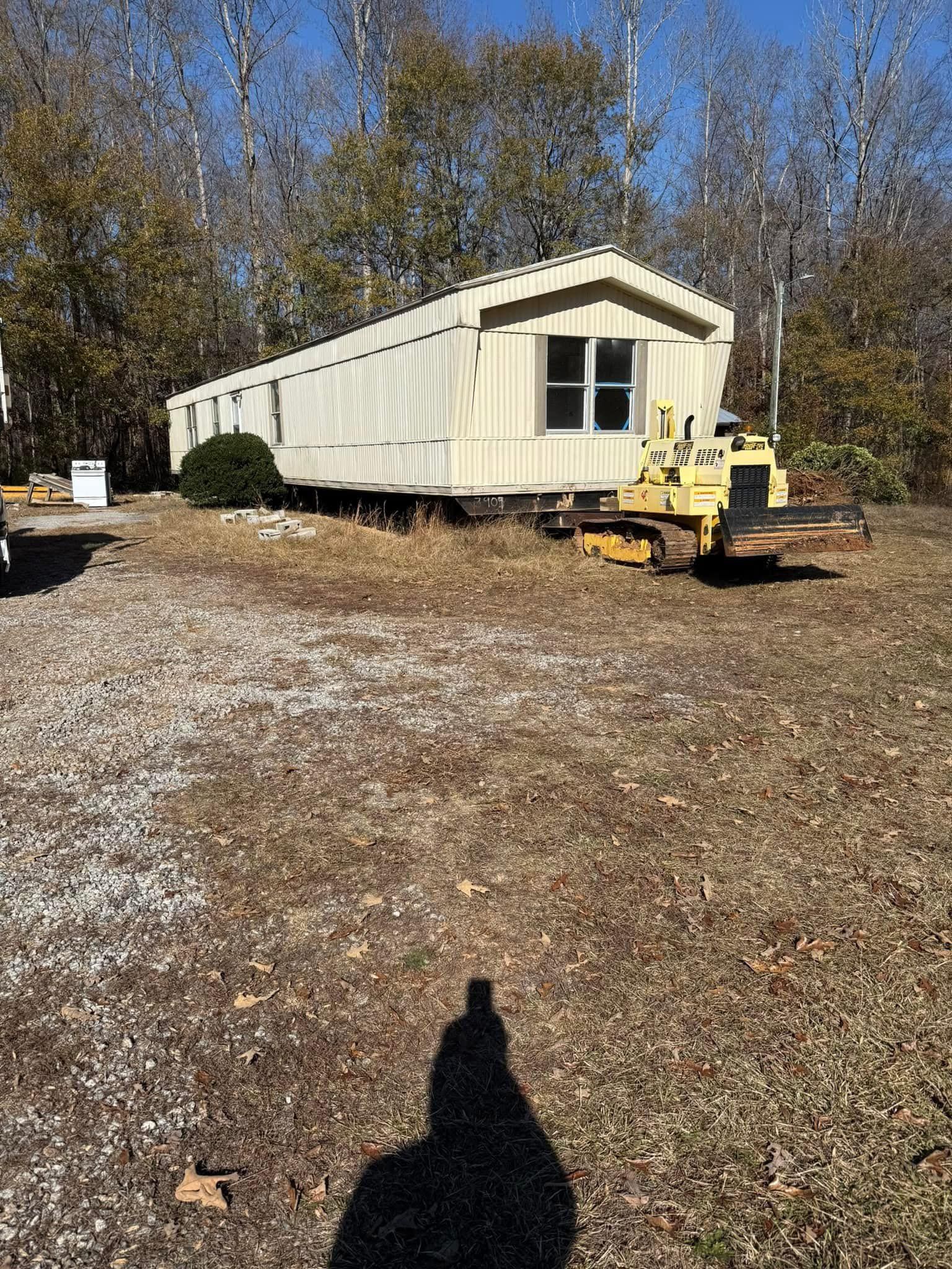 A mobile home is being moved by a bulldozer in a field.
