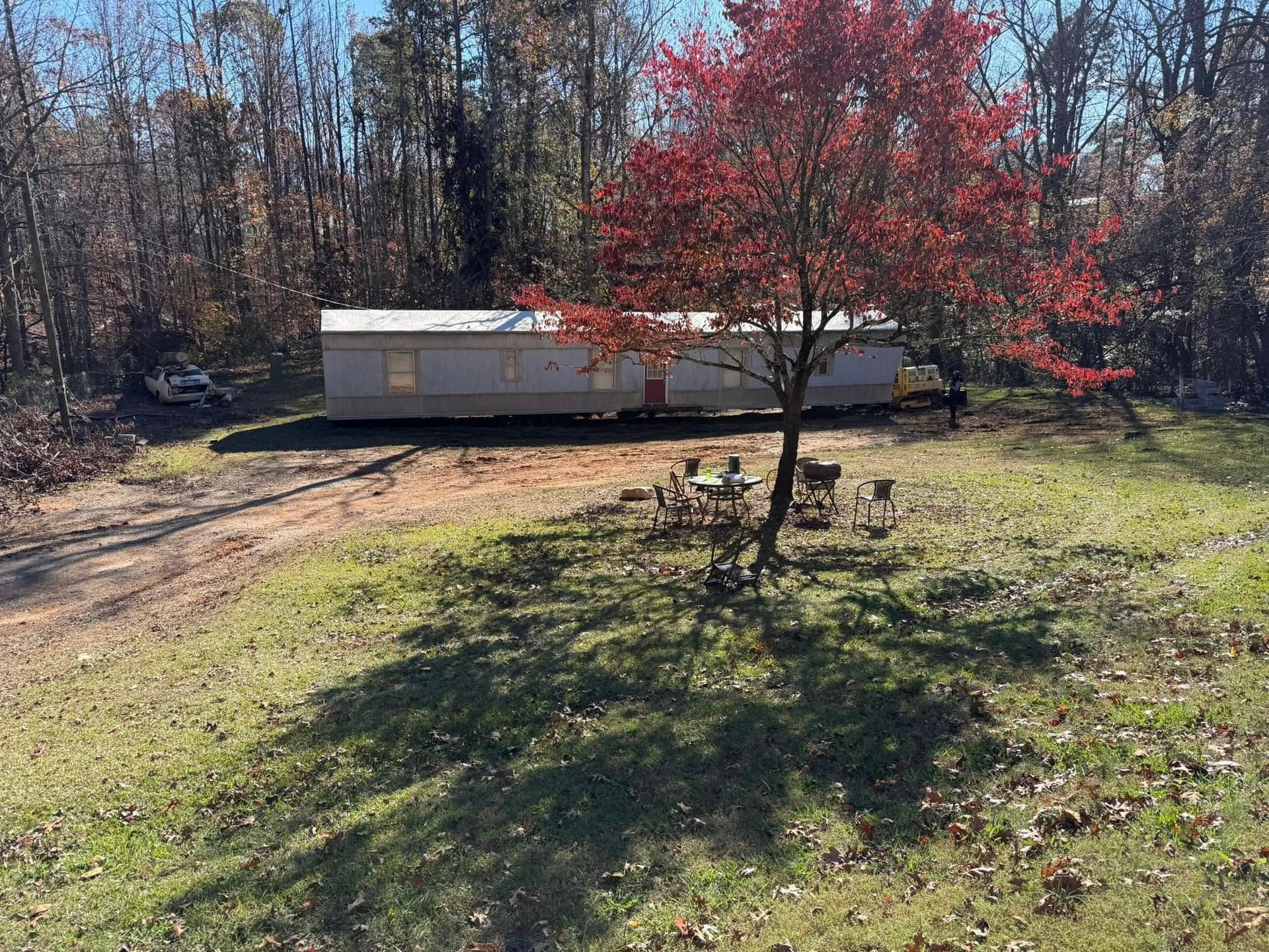 A mobile home is parked in a grassy field next to a tree.