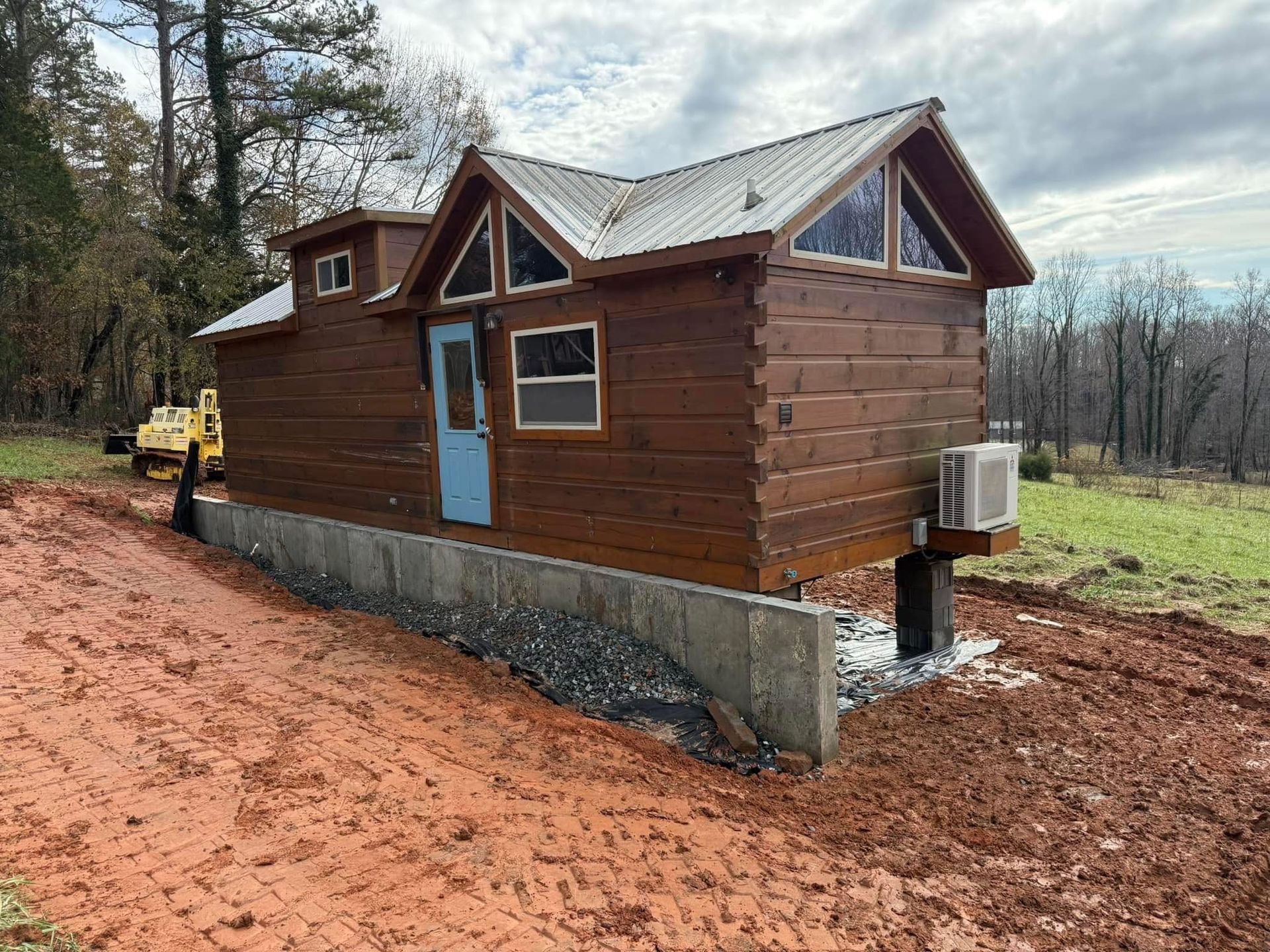 A small log cabin is sitting on top of a dirt field.