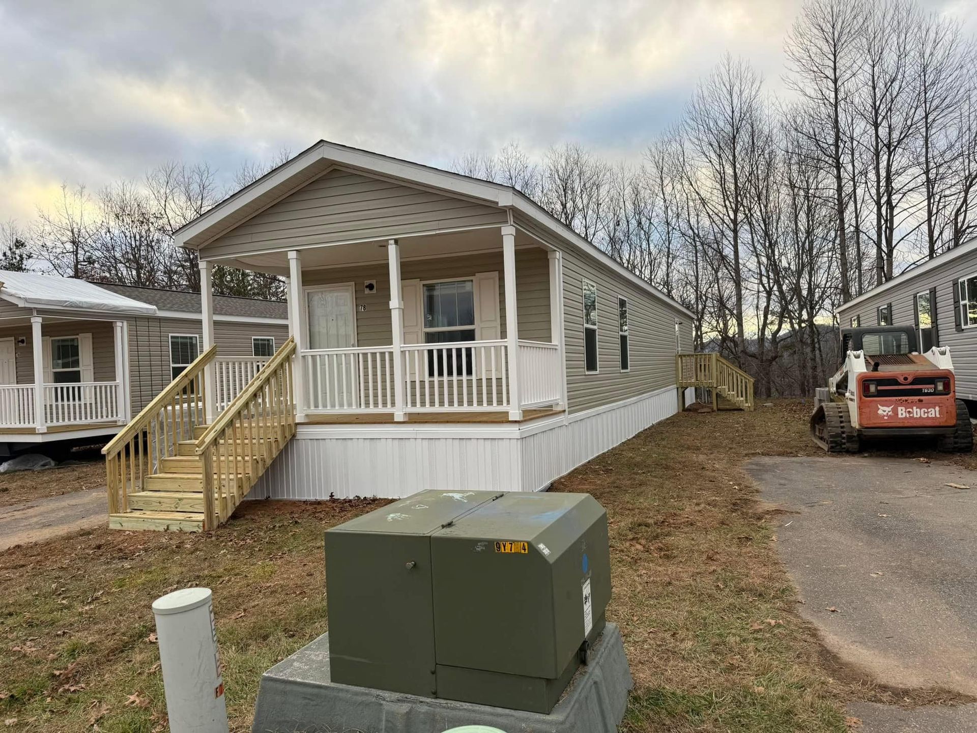 A mobile home with a porch and stairs is for sale.
