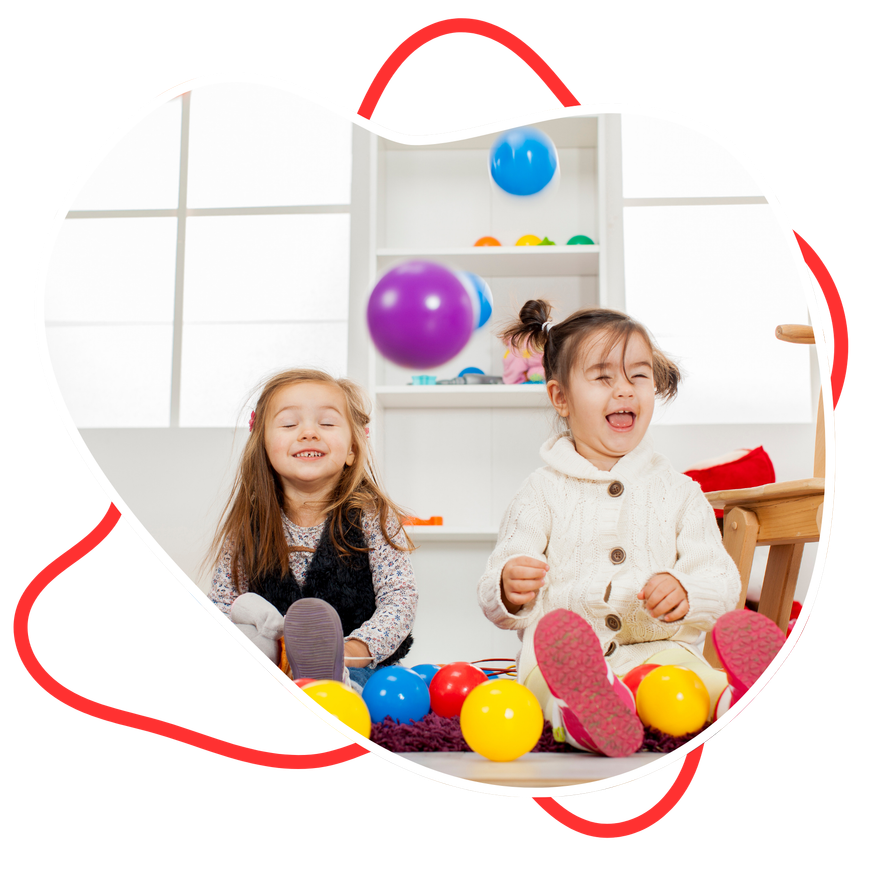 Two little girls are sitting on the floor playing with balls.