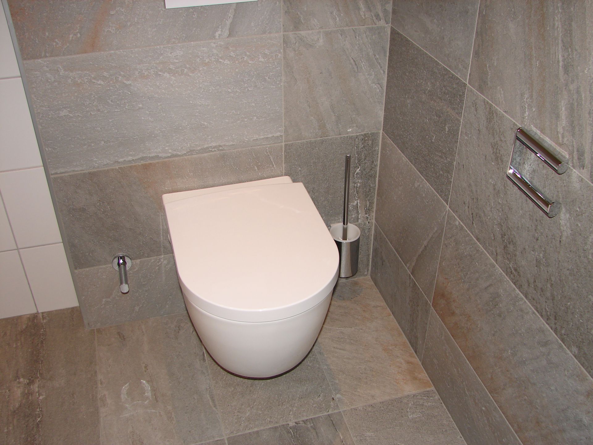 A white toilet is sitting in a bathroom next to a wall.