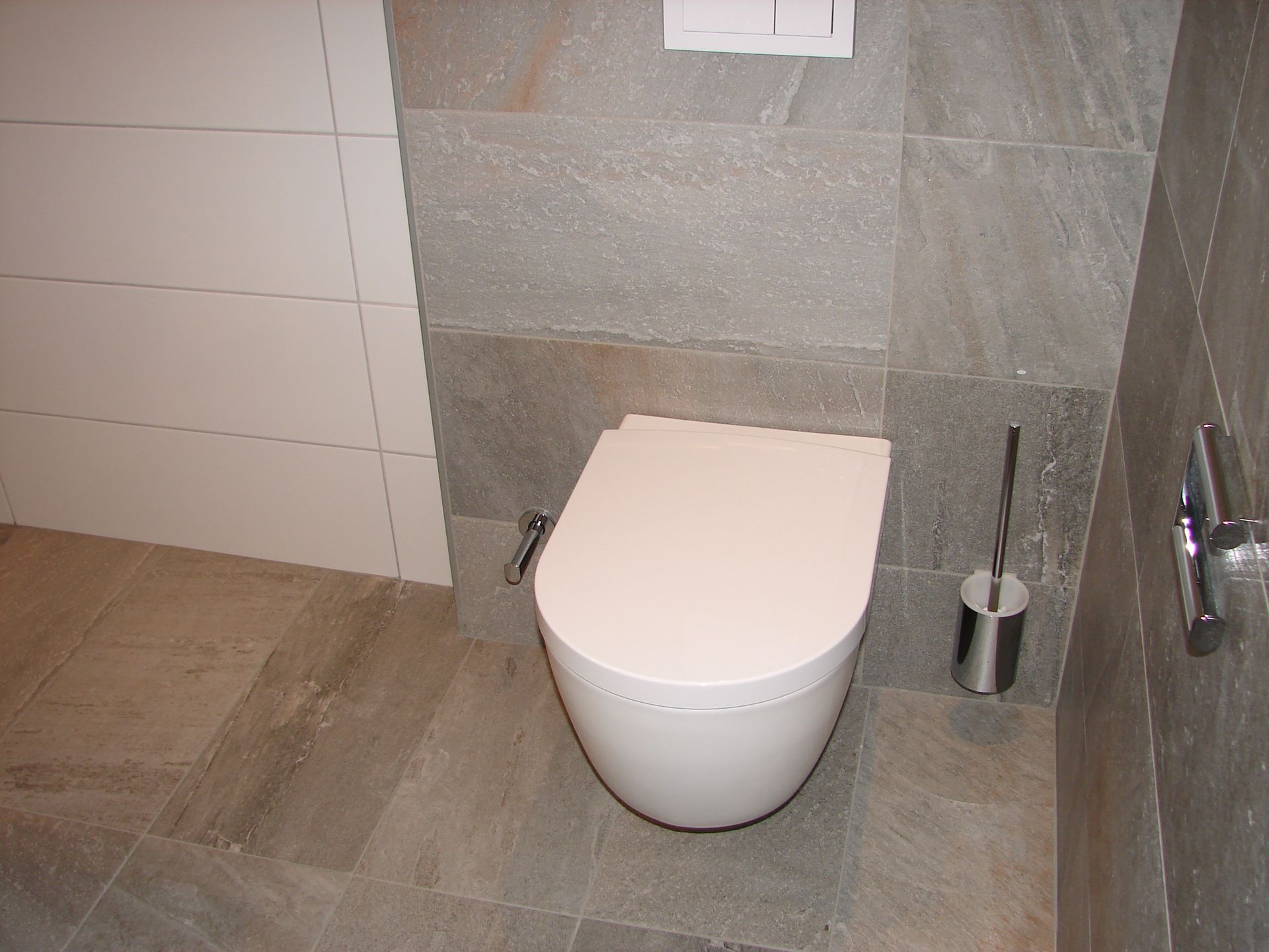 A bathroom with a toilet and a brush on the floor