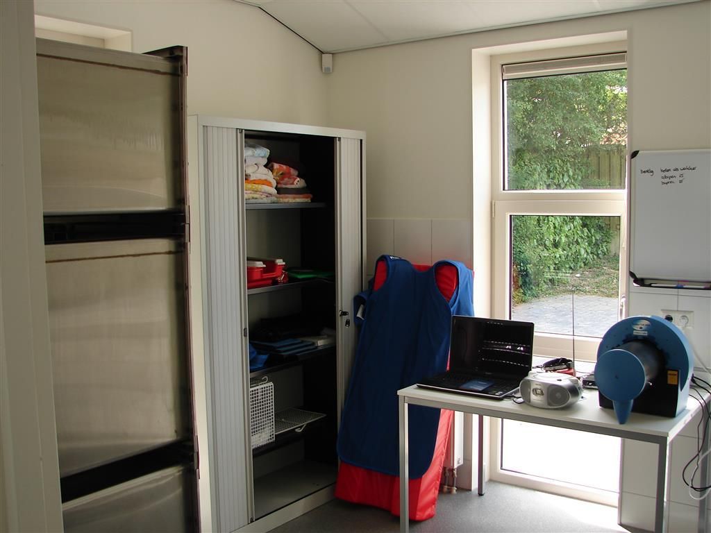 A room with a stainless steel cabinet and a table with a laptop on it