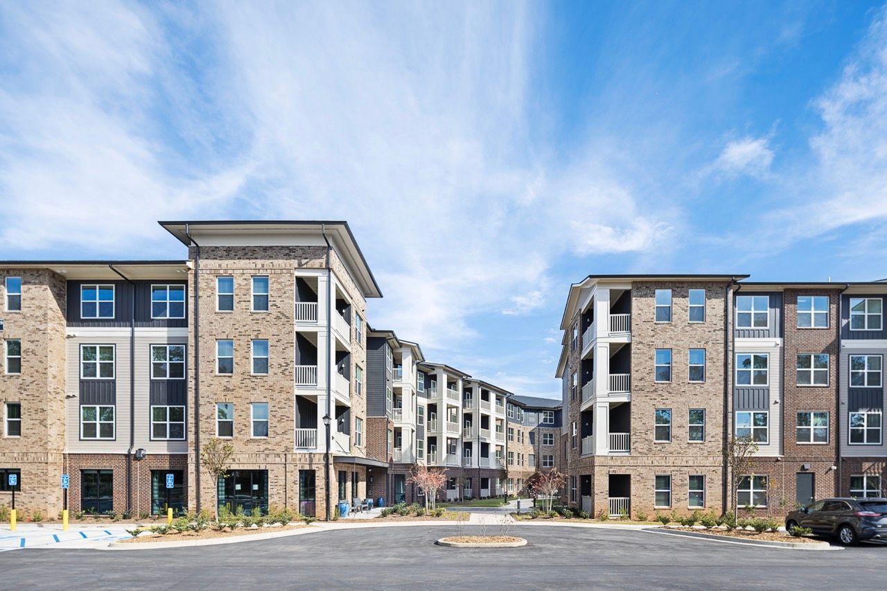 Exterior view of a modern apartment community with brick and siding buildings and a circular driveway.