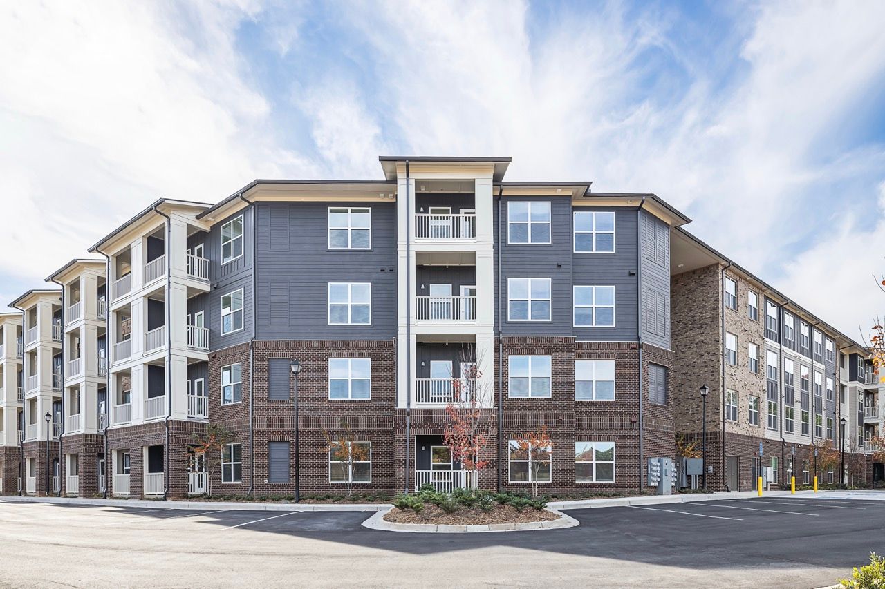 Exterior view of a modern multi-story apartment building with brick lower level and blue siding.