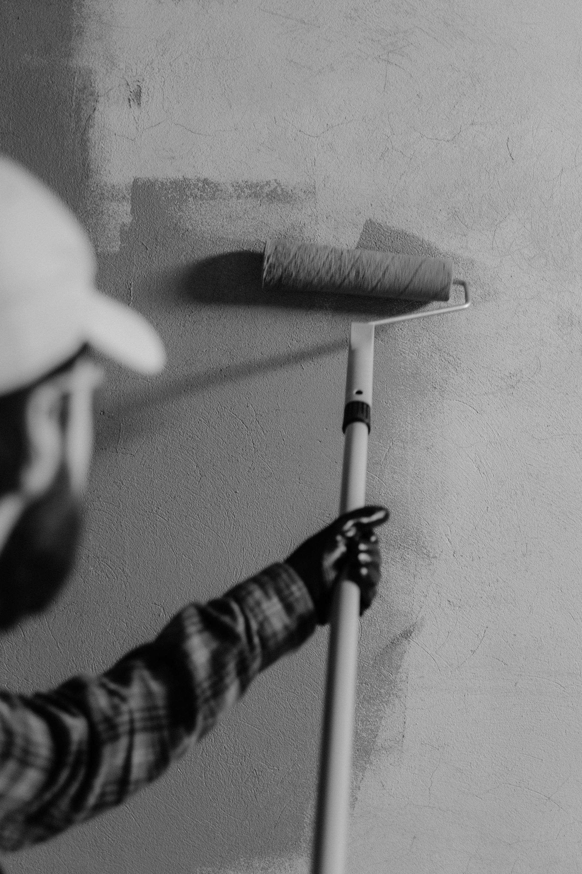 Person with a paint roller painting a wall indoors.