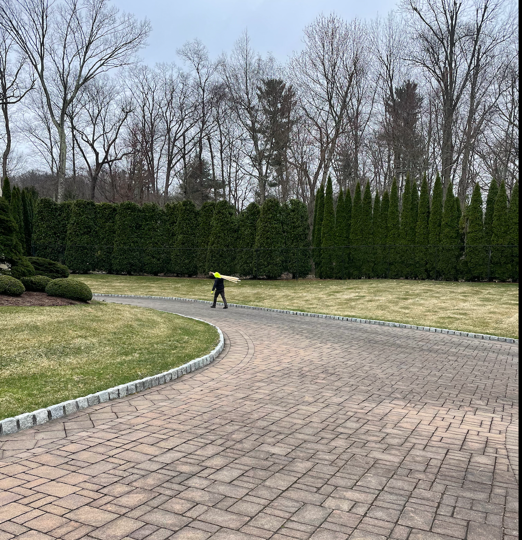 A person is walking down a brick driveway in a park.