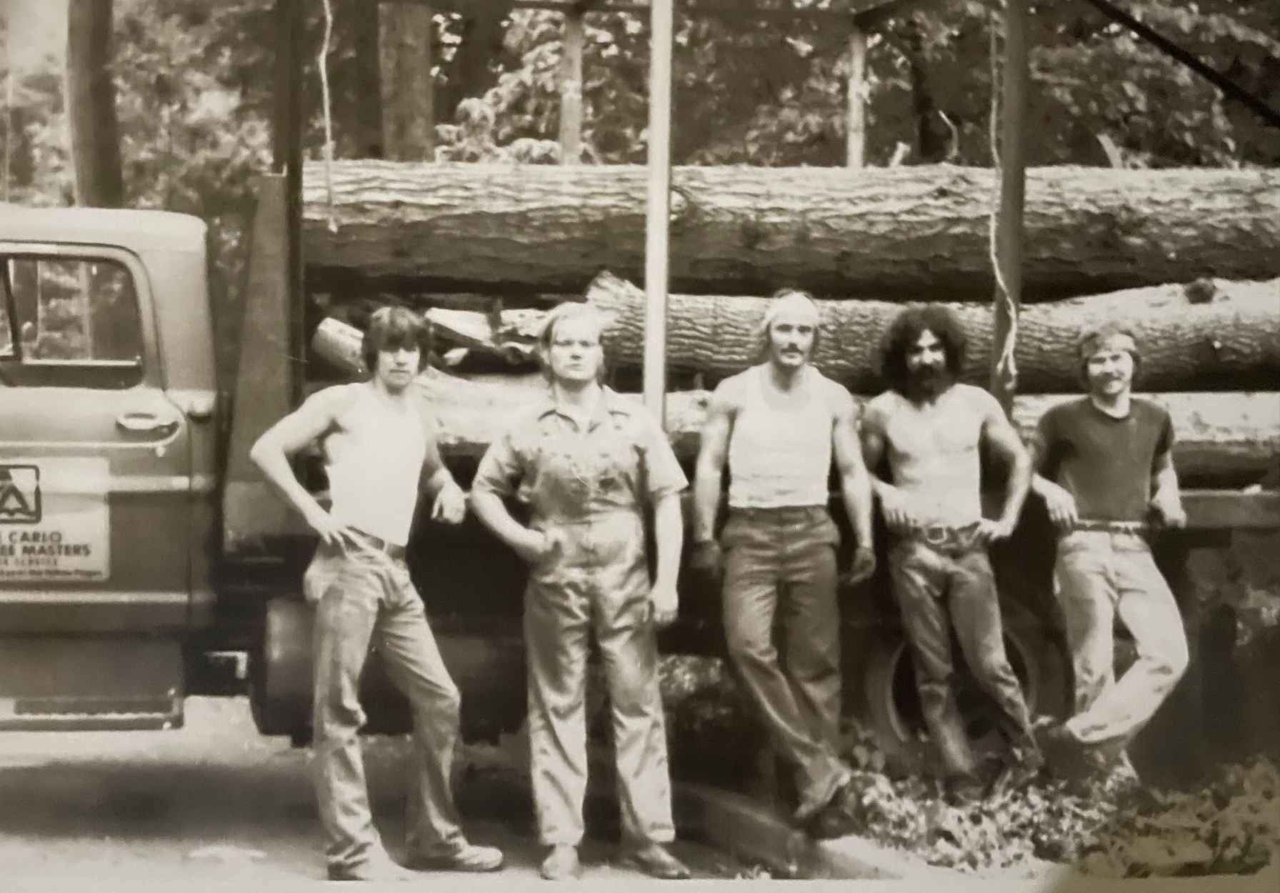 A black and white photo of men standing in front of a truck