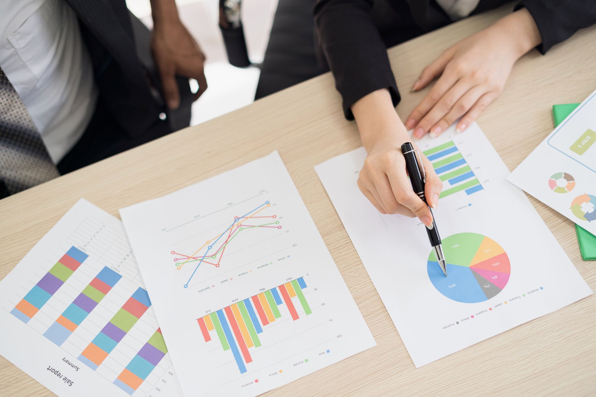 A group of people are sitting at a table looking at graphs and charts.